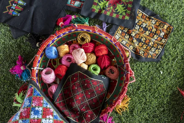 Embroidery and multi-colored balls of thread in a wicker basket on the table.