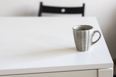 Beyaz masada iki porselen gri bardak var..