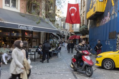 İstanbul, Türkiye - 10 Nisan 2024, Ramazan boyunca Balata ilçesindeki bir kafenin verandasında insanlar oturuyor. Motosiklet süren bir adam.