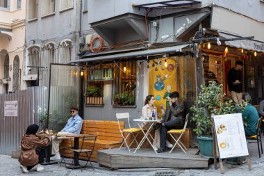 Istanbul, Turkey - April 10, 2024, People sit on the veranda of a cafe in the Balata district during Ramadan. Young people take pictures of each other. clipart