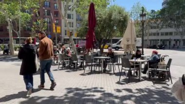Barselona, İspanya - 24 Nisan, turistler ve yerliler bir kafede oturup yemek yiyorlar. İnsanlar parkın yolu boyunca yürürler, arkadan bakarlar. Ağaçların gölgeleri.