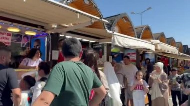 İstanbul, Türkiye - 14 Nisan 2024, Ramazan sonunda Dolmabahe Camii yakınlarındaki gıda pazarında halk şenlikleri. İnsanlar geleneksel Türk yemekleri satın alıyor.