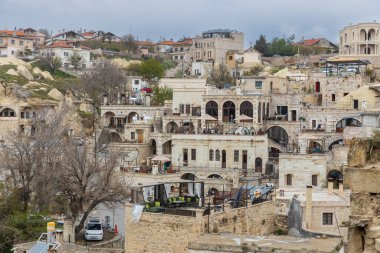 Kapadokya, Türkiye -24 Nisan 2024, Goreme kasabası yakınlarındaki Kapadokya vadisi ve ön planı ile restorandan havuza ve Ortahisar kasabasına manzara,