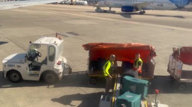 Varşova, Polonya - 20 Nisan 2024 - Frederic Chopin Havaalanı 'ndaki işçiler bavulları uçaktan boşaltıyorlar. Bagajlar taşıyıcı bant boyunca hareket eder.