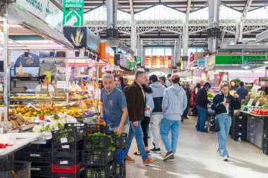 Valencia, İspanya - 24 Mart 2024: Mercado Central 'ın mimarisi, ana gıda pazarı. Neşeli bir satıcı, meyve reyonundaki müşterilere limon satıyor..