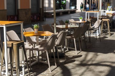 Valencia, İspanya, masaları ve hasır sandalyeleri olan açık hava kafesi. Masaların üzerinde yapay sulu bitkilerle dolu alüminyum kovalar var..