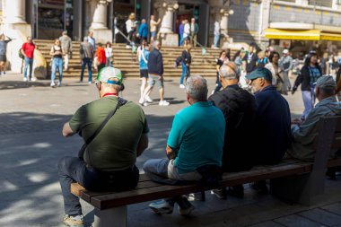 Valencia, İspanya - 20 Nisan 2024. Bir grup yaşlı adam merkez meydandaki bir bankta oturuyor..