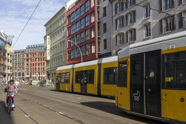 BERLIN, Almanya - 16 2024, Berlin sokak sahnesi. İyi giyimli bir adam tramvayın yanında bisiklet sürüyor..