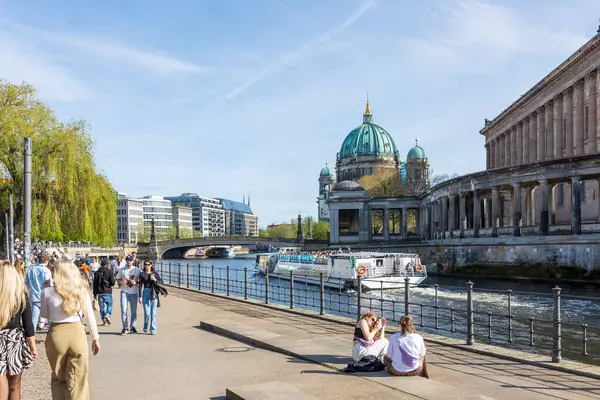 stock image Berlin, Germany - 02 April 2024, People sit on the embankment near the museum island, a boat sails along the canal - spring in Berlin.