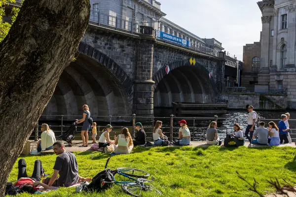 Stock image Berlin, Germany - 02 April 2024, People are sitting on the embankment. Spring in Berlin. A pleasure boat with groups of cheerful people is sailing along the canal.