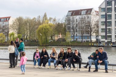 Berlin, Almanya - 02 Nisan 2024, Ren Nehri 'nin kenarında oturan insanlar müzik dinliyor..
