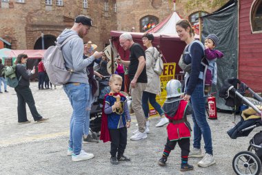 Berlin, Almanya - 30 Mart 2024: Ortaçağ Fuarı: Bir şövalye turnuvasını ziyaret edenler. Ortaçağ şövalyeleri gibi giyinmiş çocuklu bir aile..