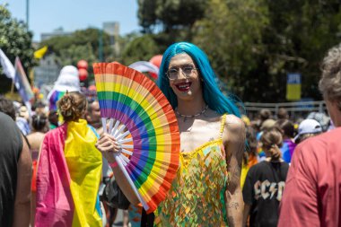 Hayfa, İsrail 21 Haziran 2024, Onur Yürüyüşü. Kalabalıkta makyajlı ve gökkuşağı bayraklı insanlar.