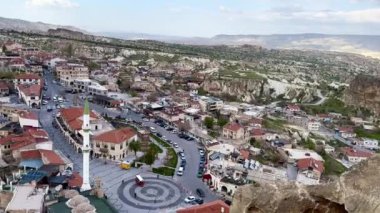 Kapadokya, Türkiye -24 Nisan 2024, Ortahisar şehri ön planda caminin minaresi ve arka planda Goreme kasabası yakınlarındaki Kapadokya vadisi yer almaktadır.,