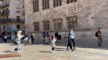 Valencia, İspanya - 20 Mayıs 2024. Bir sokak müzisyeni kız turistler geçerken şehir merkezinde flüt çalıyor..
