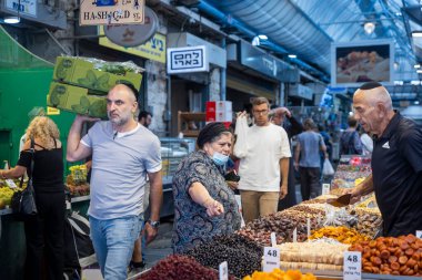 Kudüs, İsrail - 1 Ekim 2024. Mahane Yehuda pazarında sebze satan bir adam koridorda bir kutu sebze taşıyor..