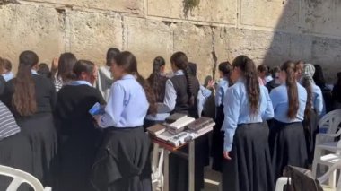 Kudüs, İsrail - 5 Ekim 2024 Ortodoks Yahudi ilahiyat fakültesi öğrencileri, kızlar, eşleşen mavi bluzlar ve siyah eteklerle Sukkot arifesinde Batı Duvarı 'nda dua ediyorlar.