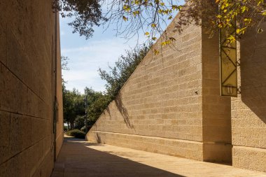 Parka giden taştan bir geçit duvarı, güneşten gelen keskin gölgeler, tropik yeşillik..
