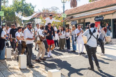 Zichron Yaakov, İsrail - 12 Kasım 2024, bir düğüne katılmak için bir aile toplandı. Herkes beyaz giyinmiş, kippah giymiş adamlar. Adamlardan birinin tüfeği var..