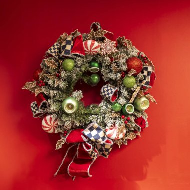 Yeşilden yapılmış bir çelenk Noel süsleri, pembe güller, kurumuş otlar ve altın boyalı yapraklar, çam kozalakları ve kurdeleler bir çiçekçinin duvarını süslüyor..