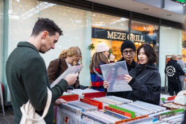 Londra, İngiltere, 22 Kasım 2024. Spitalfields Antika Pazarı. Genç bir adam ve kadın müzik çalan masalardan birinden vinil plaklar seçiyorlar..