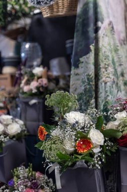 Soluk leylak-pembe güller, eryngium, eğrelti otu yaprakları ve gerberalardan oluşan çeşitli durumlar için buketler bir bit pazarında satılık antika eşyalar ve bibloların yanına konur..