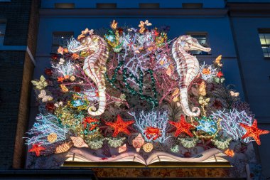 Londra, İngiltere - 2 Aralık 2024: Christian Dior Noel vitrini, deniz teması. Pembe deniz atları, deniz yosunu, mercan, denizyıldızı, el çantası, masa, moda kitaptan fırladı.