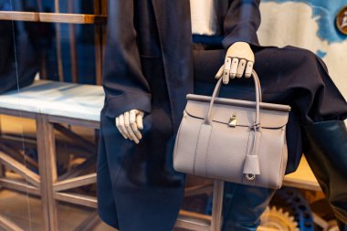 Ahşap kollu bir mankenin elinde isimsiz bir bej çanta..