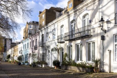 Londra, İngiltere - 1 Aralık 2024, Ennismore Gardens Mews Caddesi, popüler bir yer. Güneşli havada ağaç gölgeli renkli evlerin olduğu bir cadde..