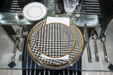 Masa bir kutlama için hazırlandı. Siyah köknar ağacı desenli beyaz tabaklar, gümüş çatal bıçak takımı, peçeteler ve şarap bardakları..