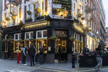 Londra, İngiltere - 23 Kasım 2024, Beyaz Aslan barının dışındaki masalarda oturan insanlar, bira içip sohbet ediyorlar. Covent Bahçesi