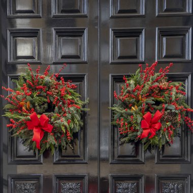 Kırmızı yay ve kırmızı böğürtlenli köknar ya da ladin dallarından iki çelenk.