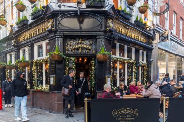 Londra, İngiltere - 3 Aralık 2024, Covent Garden 'daki White Lion barından ayrılan insanlar.