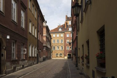 Warsaw, Poland - September 2, 2024, Houses and streets of the Old Town, the road is paved with cobblestones. Windowsills are decorated with flowerpots containing blooming geraniums. clipart