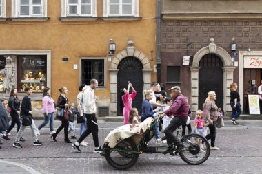 Varşova, Polonya - 2 Eylül 2024, triportöre binen bir adam kalabalığa doğru gidiyor, hizmetini sunuyor. Eski kasaba. Turistler.