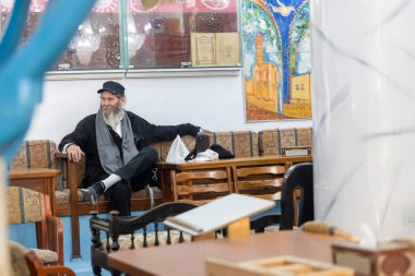 Tzfat, İsrail - 2 Ocak 2025, sinagogdaki bir masada oturan yaşlı bir adam düğün törenini bekliyor..