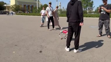 Moskova, Rusya - 23 Ağustos 2024: VDNKh parkında biyonik robot köpeği olan genç bir adam yeteneklerini sergiliyor ve bir kadınla el sıkışıyor..