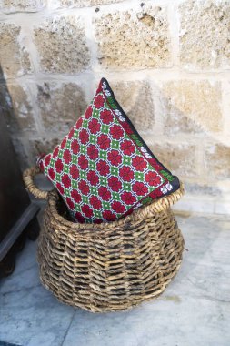İç dekorasyon için dokuma sepetine Doğu Arap tasarımlarını gösteren kırmızı işlemeli çiçekli bir yastık..