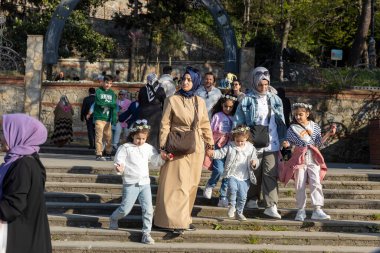 İstanbul, Türkiye 2 Mayıs 2024, rüzgarlı bir günde dört çocukla birlikte parka inen türban takan iki kadın.