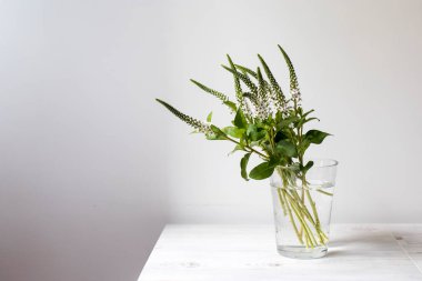 Düğün buketi ya da Veronica Longifolia 'nın açık arkaplanlı bej ahşap bir masada cam bir vazoda bulunduğu Sevgililer Günü buketi. Kopyalama alanı