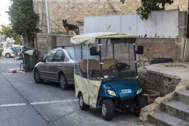 Hayfa, İsrail, 2 Mart 2025. Wadi Nisnas bölgesi. Çatıda bir Alman kurdu duruyor. Küçük bir araba ve bir scooter park edilmiş..