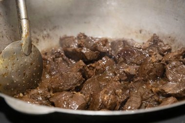 Büyük metal bir tavada haşlanmış et parçaları. yemek pilavı