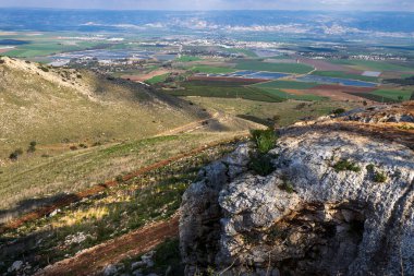 Gilboa Dağı İsrail 'den bir panorama. Çam ağaçları, bitki örtüsü, vadi ve Ürdün dağlarından oluşan bir panorama. Üzerlerinde bulutlar ve aşağıda uzanan tarım arazileri var..
