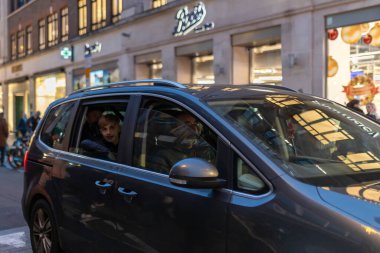 Londra, İngiltere - 1 Aralık 2024: Covent Garden bölgesinde yolcuları olan siyah geleneksel bir İngiliz taksisi, yoğun caddelerden geçiyor..