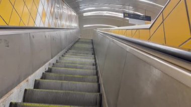 Hayfa, İsrail, 21 Mart 2025. Ha-Nevi 'im istasyonundaki Carmelit metrosunda yürüyen merdiven. Merdivenler yukarı doğru hareket ediyor. Duvarlar sarı ve beyaz karolarla kaplanmış..