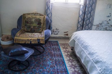 Mavi koltuklu rahat bir yatak odası köşesi dekoratif yastıklar ve desenli bir kıç.