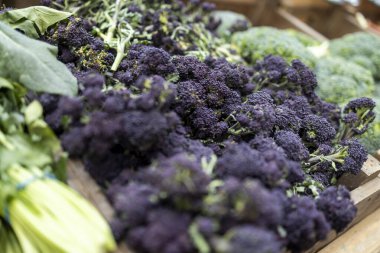 Marketteki ahşap bir sandıkta taze mor brokoli filizleniyor.