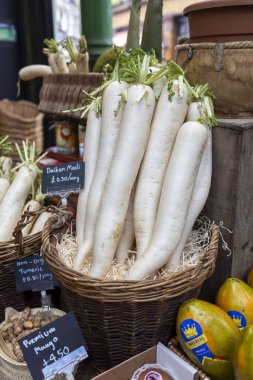 Londra, Borough pazarı, İngiltere, 23 Kasım 2024, Fresh Daikon turpları bir markette fiyat etiketleri ile bir sepette