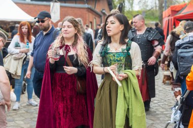 Berlin, Almanya - 30 Mart 2024: Ortaçağ Fuarı: Easter Knight Spectaculum. Spandau Kalesi 'ndeki bir ortaçağ pazarında ortaçağ kostümlü iki kadın bardak taşıyor.,