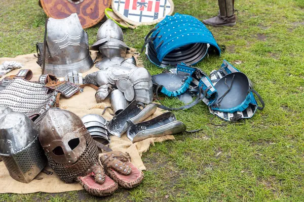 Ortaçağ zırhı ve miğferleri yeşil çimen tarlasında serilmişti. Tarihi bir canlandırmada bile.